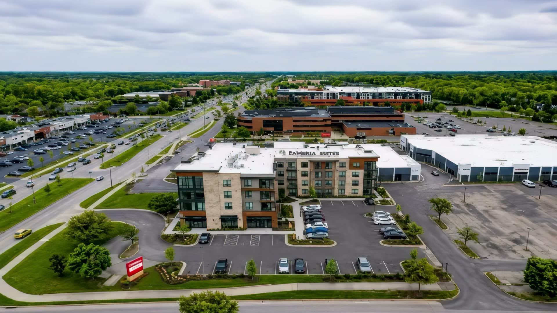 Aerial view of the Orchard Lake Road commercial corridor in West Bloomfield, Michigan — hotel, retail and office frontage along the highway.