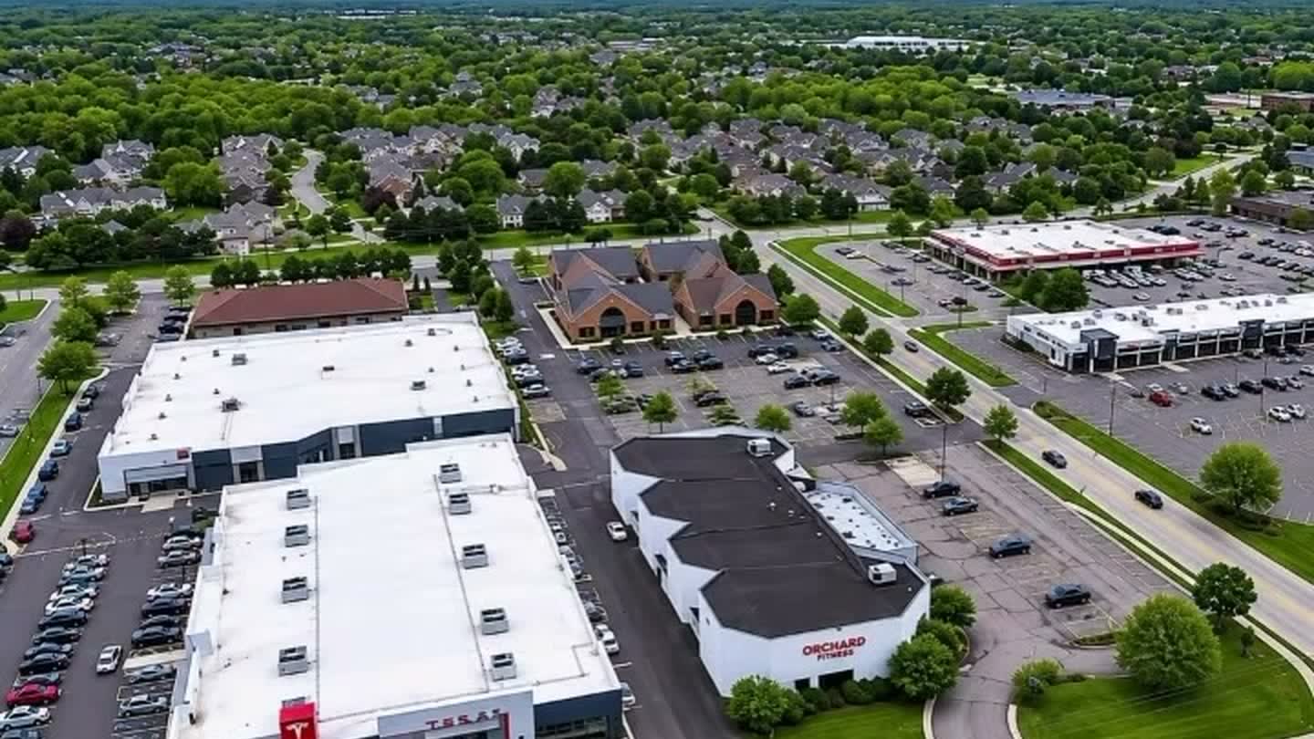 Drone view of the Orchard Lake Road commercial corridor in West Bloomfield, showing retail buildings and parking along the road frontage.
