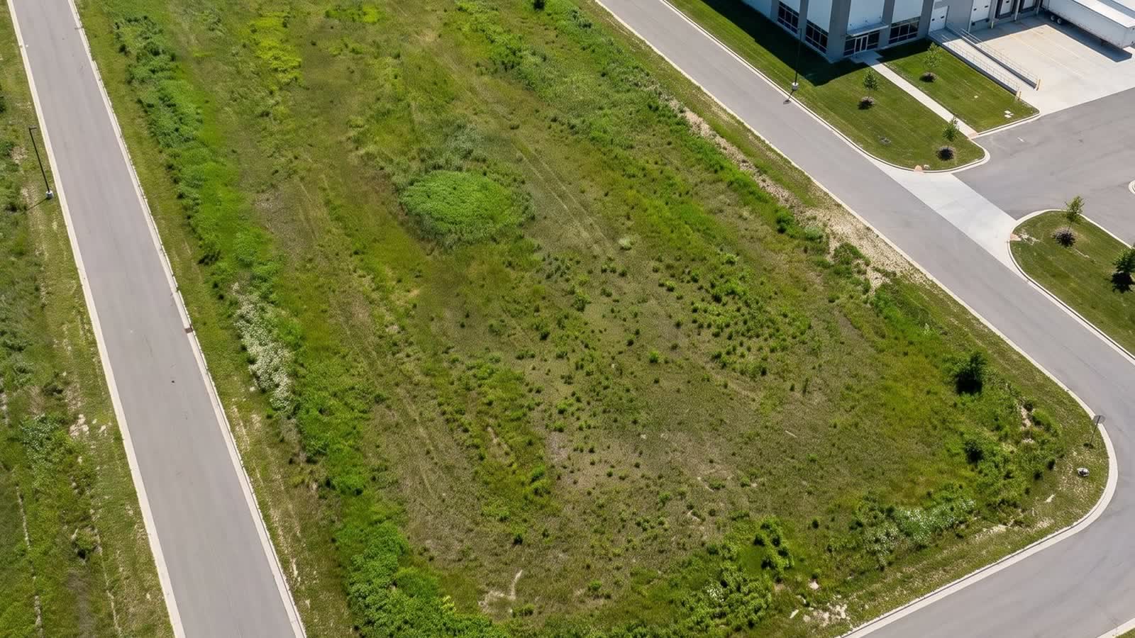 Aerial view of an approved commercial land parcel bordered by road frontage in suburban Michigan.
